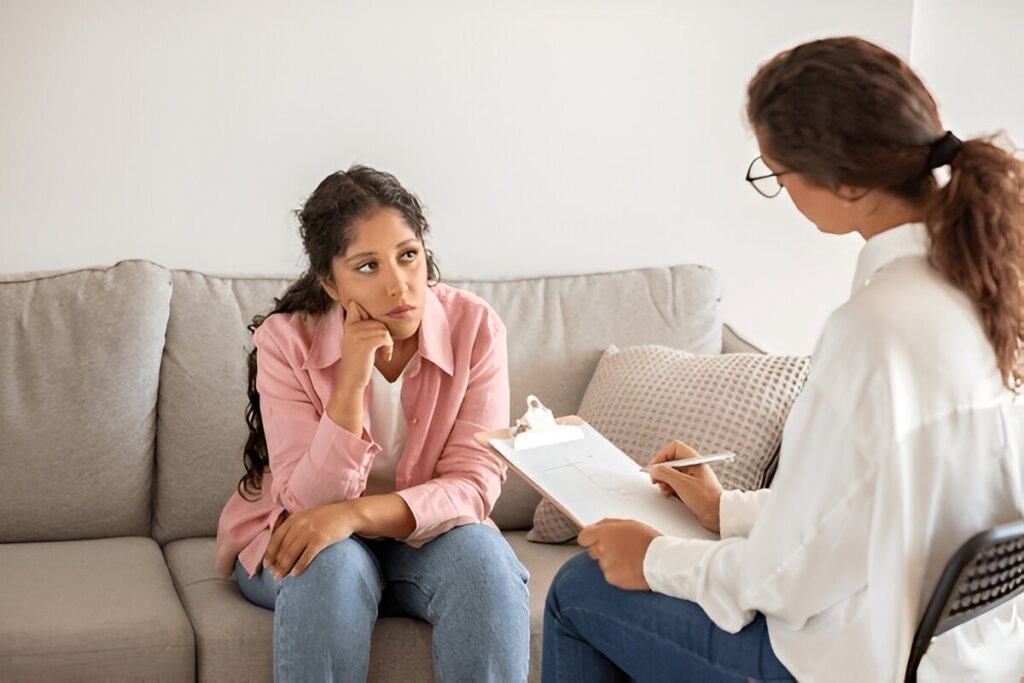 Woman in therapy session with counselor holding clipboard
