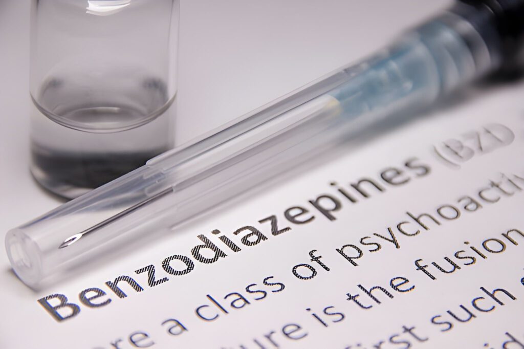 Syringe and vial placed over text highlighting the word "Benzodiazepines (BZD)".