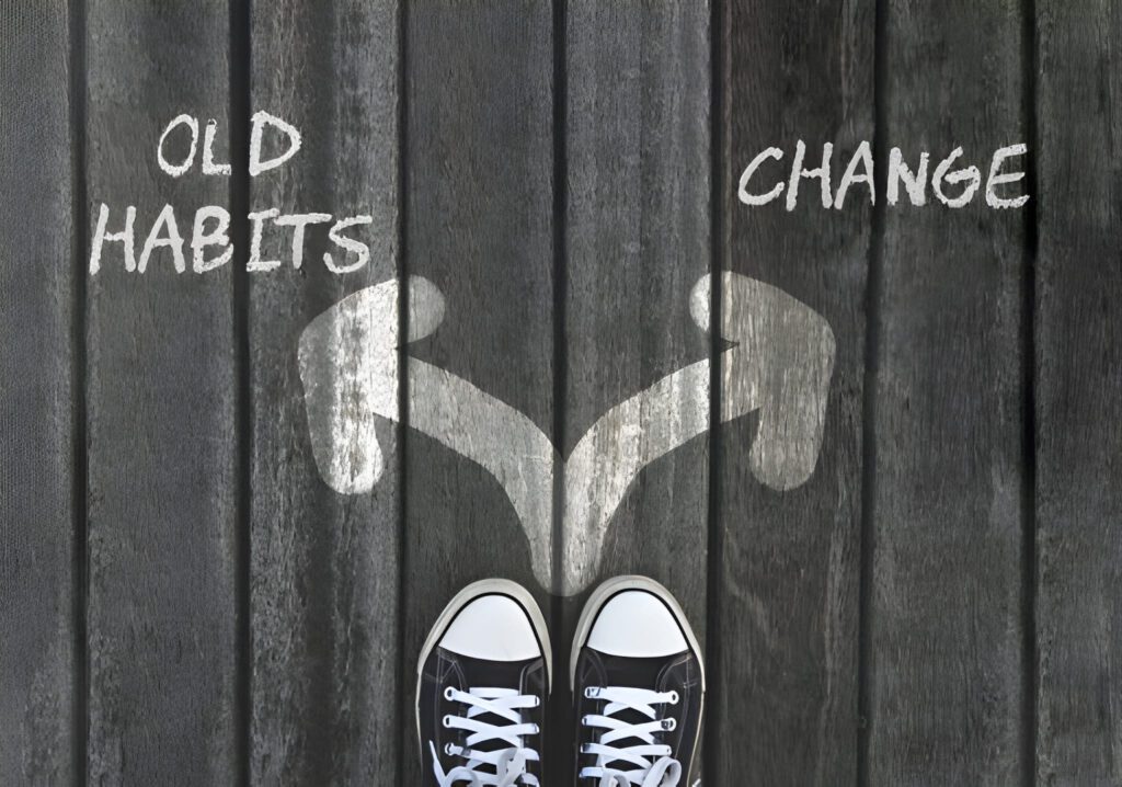 Shoes at a fork in the road with arrows labeled 'Old Habits' and 'Change'