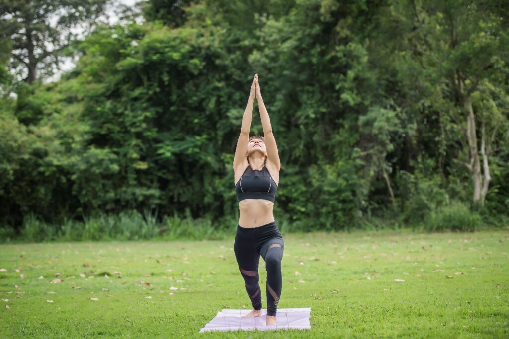 A person doing yoga on a mat in a grassy area