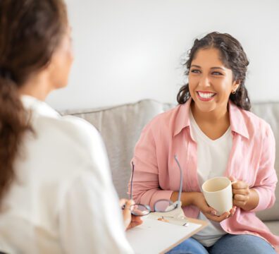 Smiling woman in conversation on a couch.