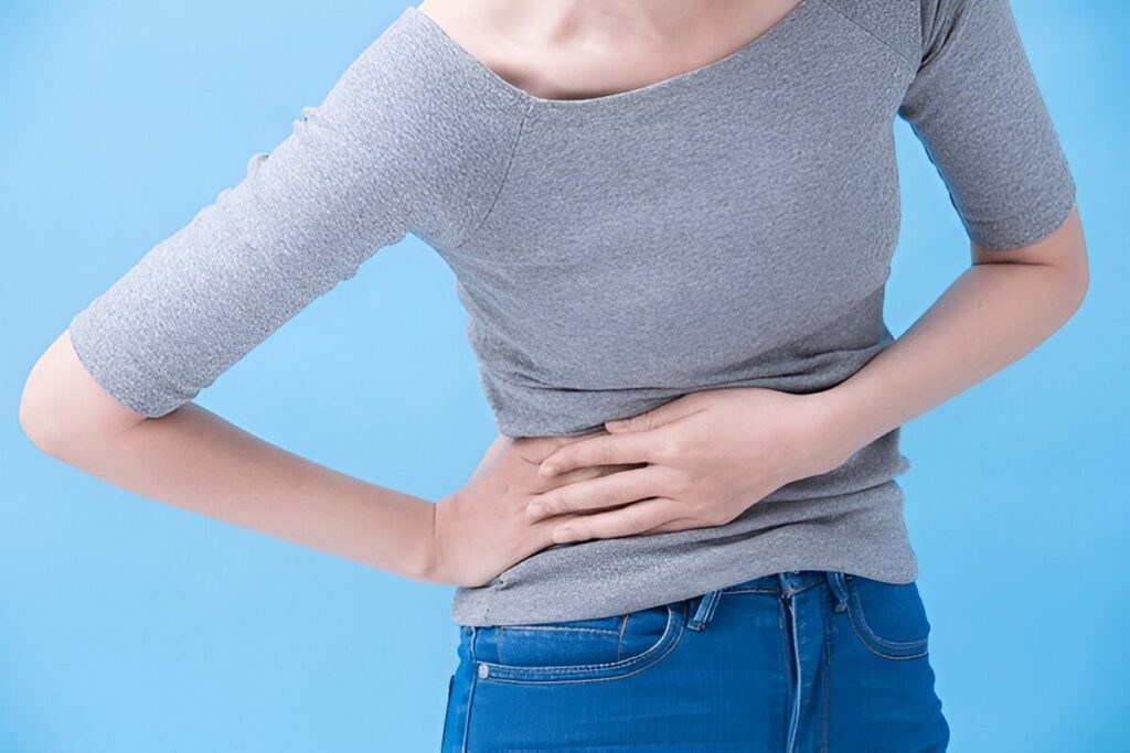 Woman holding her side, suggesting pain or discomfort in the upper abdomen/rib area.