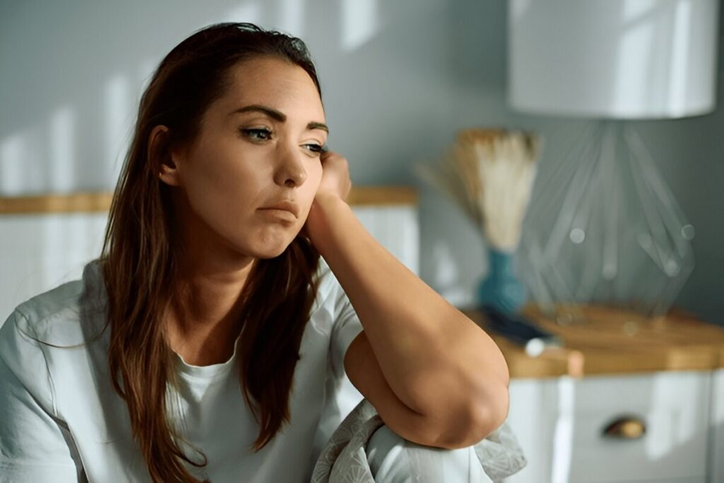 Unhappy woman with a pensive, sad, or depressed expression sitting and leaning on her arm.