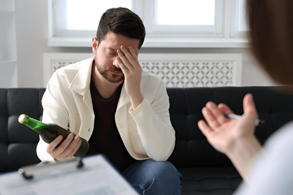 Distressed man with an alcohol bottle in a therapy session.